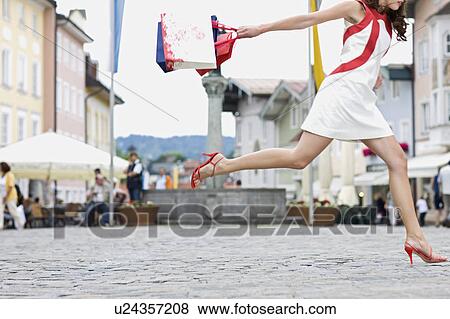 Stock Photo - woman runs through a shopping street. Fotosearch