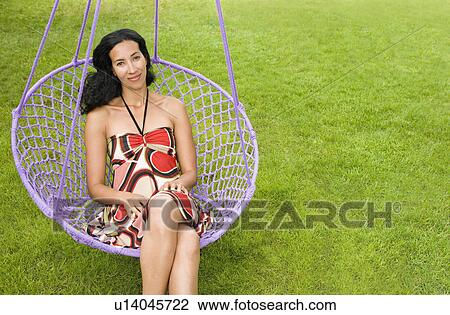 Stock Image - woman sitting on a swing. Fotosearch