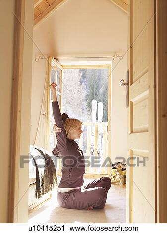 Stock Image - woman sitting on bedroom floor in chalet. Fotosearch
