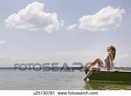 Stock Image - woman sitting on boat on lake. Fotosearch
