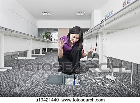 Stock Image - woman struggling with hi tech cables. Fotosearch