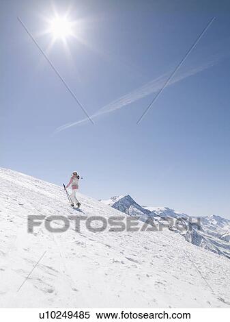 Stock Photography - woman walking up mountain with skis. Fotosearch