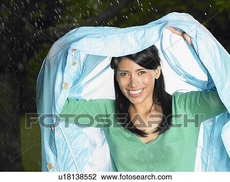 Stock Image - Woman with jacket over her head, rain. Fotosearch