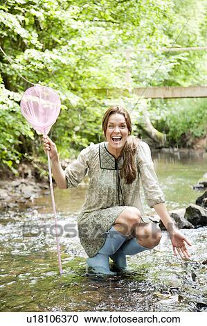 Stock Image - Woman with net splashed in stream. Fotosearch