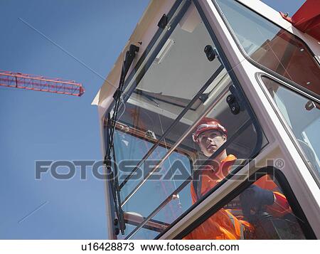Stock Image - Worker Controlling Crane From Cabin. Fotosearch