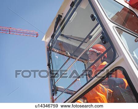 Stock Photo - Worker Controlling Crane From Cabin. Fotosearch