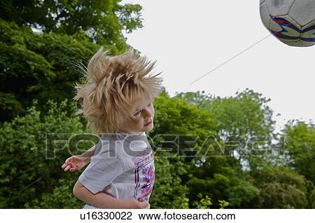 Stock Image - Young boy heading a football.. Fotosearch