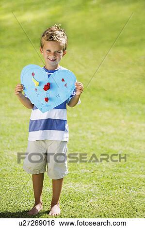 Stock Photograph - Young boy holding blue paper heart. Fotosearch