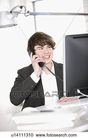 Young Businessman sitting behind a computer View Large Photo Image Stock Image - Young Businessman sitting behind a computer. Fotosearch
