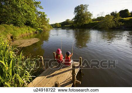 Stock Image - Young girl and boy fishing.. Fotosearch