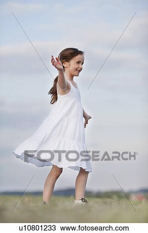 Stock Image - young girl dancing in the grass. Fotosearch