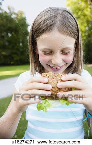 Stock Image - Young Girl Eating Burger. Fotosearch