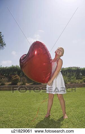 Young girl holding big red heart balloon View Large Photo Image Stock Image - Young girl holding big red heart balloon. Fotosearch