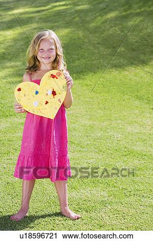 Stock Image - Young girl holding paper heart. Fotosearch