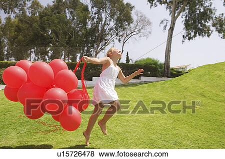 Young girl jumping with red balloons View Large Photo Image Stock Photo - Young girl jumping with red balloons. Fotosearch