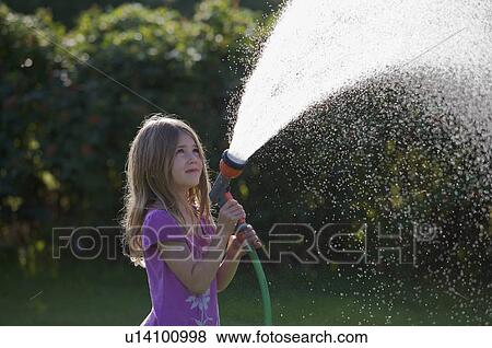 Stock Photo - Young girl spraying water with a hose. Fotosearch