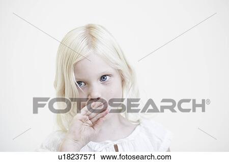 Stock Image - Young girl with hand up to mouth. Fotosearch