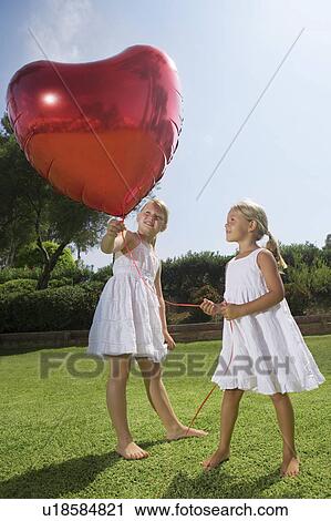 Young girls holding red heart balloon View Large Photo Image Stock Image - Young girls holding red heart balloon. Fotosearch
