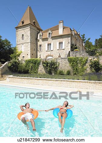 Stock Photo - young man and woman floating in pool. Fotosearch