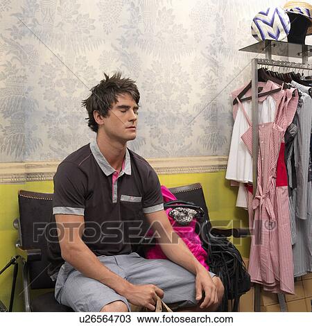 Stock Image - Young man waiting + relaxing in shop. Fotosearch
