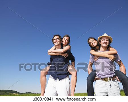 Stock Image - young people riding piggy back. Fotosearch