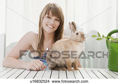 Picture - Young woman and a pet rabbit on a patio. Fotosearch