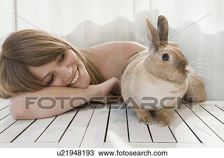 Stock Image - Young woman and a pet rabbit on a patio. Fotosearch