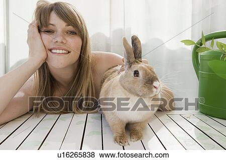 Stock Photo - Young woman and a pet rabbit on a patio. Fotosearch