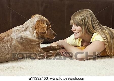 Stock Image - Young woman and dog lying on the floor. Fotosearch