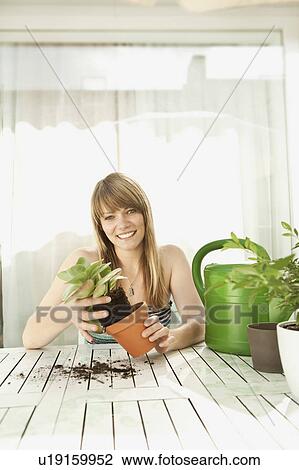 Stock Image - Young woman and plants on patio. Fotosearch
