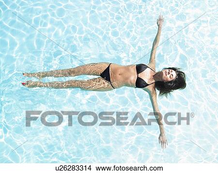 Picture - young woman floating in pool. Fotosearch