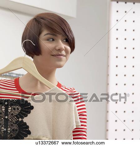 young woman holding an item of clothing View Large Photo Image Stock Photo - young woman holding an item of clothing. Fotosearch