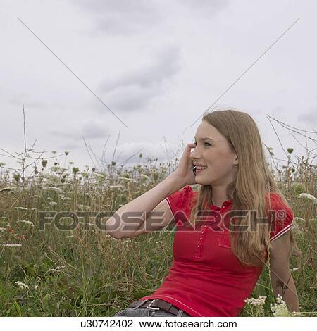 Young woman in grass with mobile phone View Large Photo Image Stock Image - Young woman in grass with mobile phone. Fotosearch