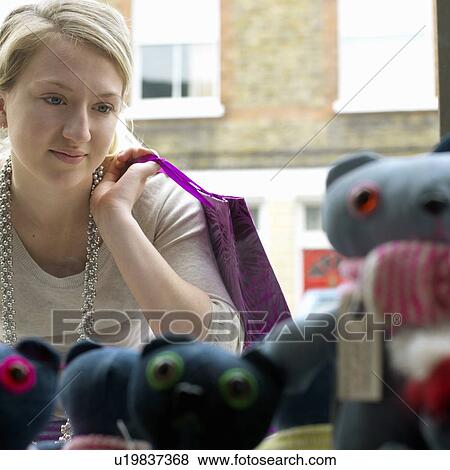 Young woman looking at shop window View Large Photo Image Stock Photo - Young woman looking at shop window. Fotosearch