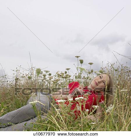 Young woman lying in high grass and flower View Large Photo Image Stock Image - Young woman lying in high grass and flower. Fotosearch