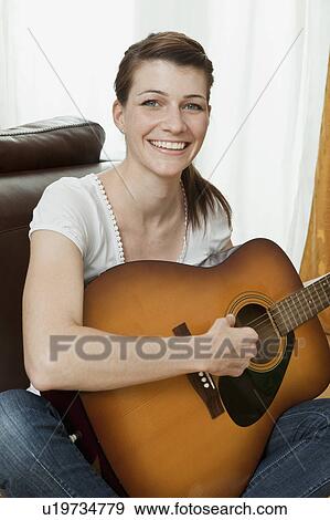 Stock Photo - Young woman playing the guitar. Fotosearch