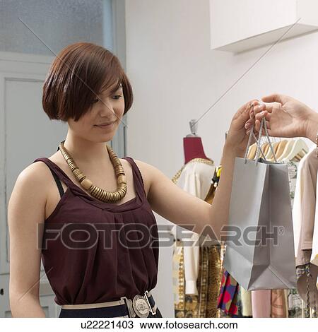 Stock Image - young woman receiving paper bag. Fotosearch