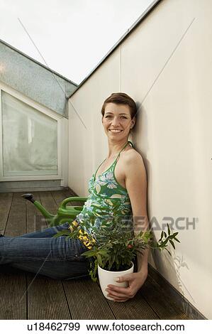 Stock Photo - Young woman sitting on patio floor. Fotosearch
