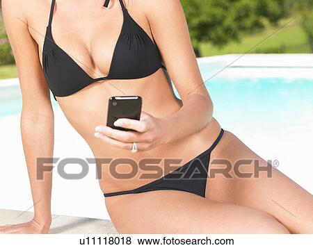 Stock Photo - young woman using phone by pool. Fotosearch
