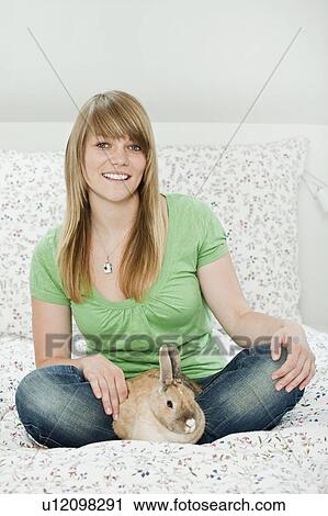 Stock Image - Young woman with pet rabbit. Fotosearch