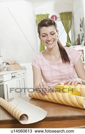 Stock Image - Young woman wrapping a gift. Fotosearch