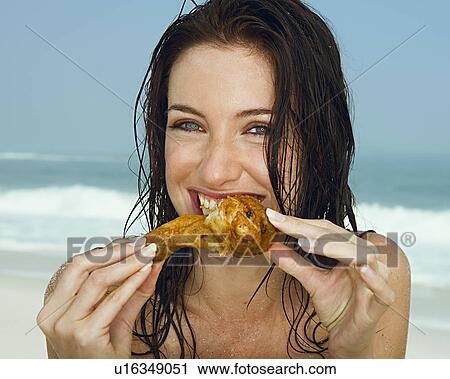 Stock Image - Young women eating a chicken leg. Fotosearch