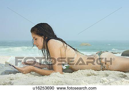 Stock Image - Young Women on Beach reading a book. Fotosearch