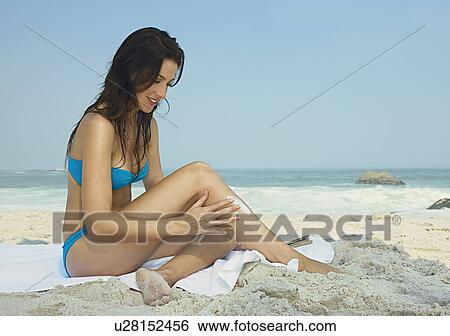 Young women putting cream on at a beach View Large Photo Image Stock Photograph - Young women putting cream on at a beach. Fotosearch