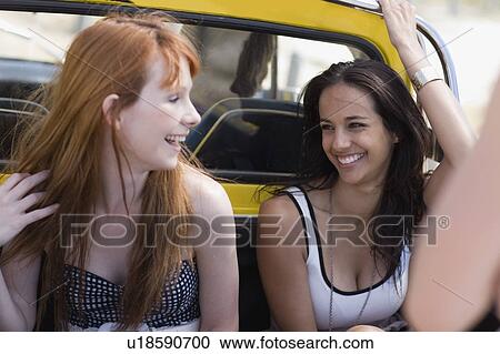 Stock Image - 2 Girls sitting on back of pickup. Fotosearch