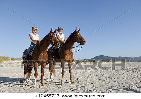 2 people riding horses on the beach View Large Photo Image Stock Photo - 2 people riding horses on the beach. Fotosearch