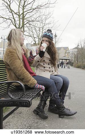 Stock Photo - 2 women in the park with take away cups. Fotosearch