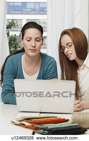 Stock Photo - 2 women looking at a laptop. Fotosearch
