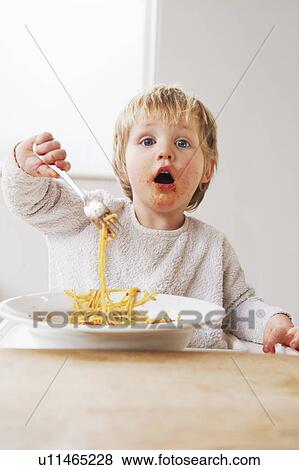 Stock Photo - 2 year old boy eating spaghetti. Fotosearch