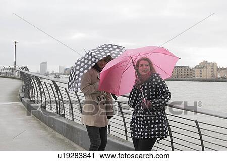 2 yougn women with umbrellas by river View Large Photo Image Stock Image - 2 yougn women with umbrellas by river. Fotosearch